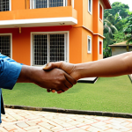 A landlord and tenant shaking hands in front of a well-maintained house, symbolizing a positive relationship. Include elements representing rights and responsibilities, like a contract or a key. Bengali script in the background.